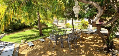 a dining table and chairs under a tree in a yard at LAKAZ DEL SOL - Modern and elegant apartments with luxurious garden, pool and barbecue area - Tourism Permit Certified in Tamarin