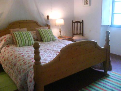 1 dormitorio con cama de madera y almohadas verdes en La Carapeteria, en Arronches