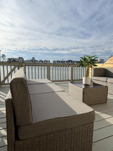 a balcony with a couch and chairs on a deck at Sunset Serenity!!-Tropical Waterfront Oasis-Huge Private Patio-10Min to KingSt & Beaches in Charleston