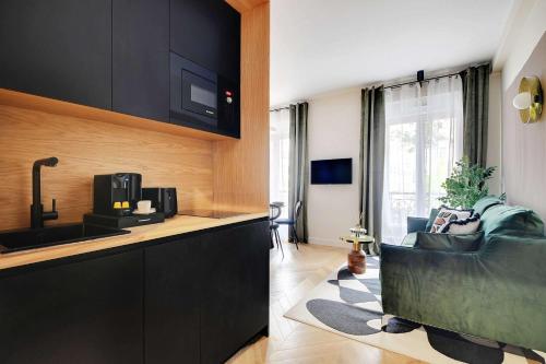 une cuisine avec des armoires noires et un salon dans l'établissement Entire apartment near the Eiffel Tower, à Paris