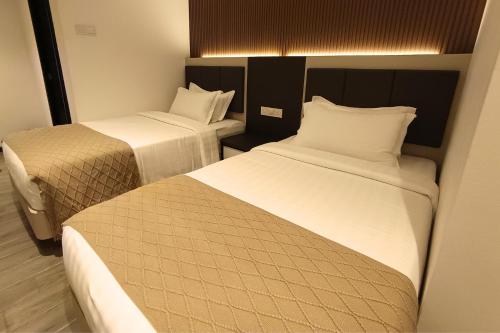 a hotel room with two beds with white sheets at De Quinton Hotel in Ipoh