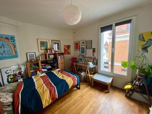 une chambre avec un lit, un bureau et une fenêtre dans l'établissement Charmant appartement artistique à Gambetta Père Lachaise, à Paris