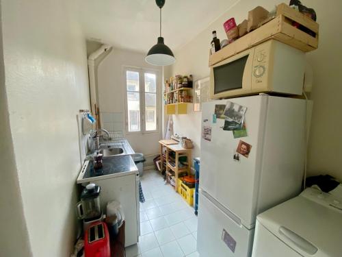 La cuisine est équipée d'un réfrigérateur blanc et d'un four micro-ondes. dans l'établissement Charmant appartement artistique à Gambetta Père Lachaise, à Paris