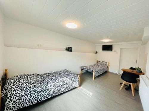 a bedroom with two beds and a table and a desk at D D Haus in Arnstein