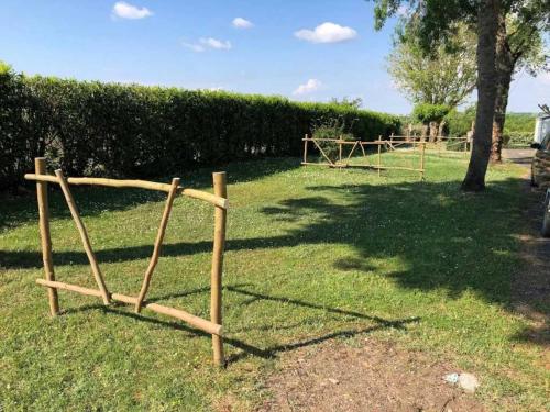 a wooden fence in the grass with a tree at Camping 3 étoiles - Piscine - ccaihff in Saint-Georges-de-Didonne