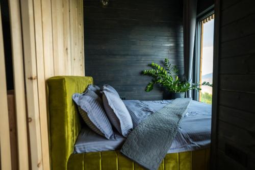 a bedroom with a green couch with pillows on it at The Altitude Cabin Resort in Măguri