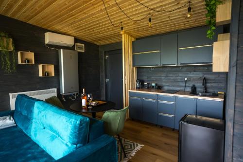 a living room with a blue couch and a kitchen at The Altitude Cabin Resort in Măguri