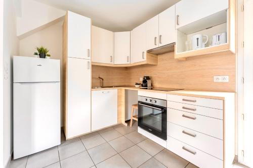 a kitchen with white cabinets and a white refrigerator at Le Mûrier - Maison de ville avec patio parking - 6 pers in Lyon