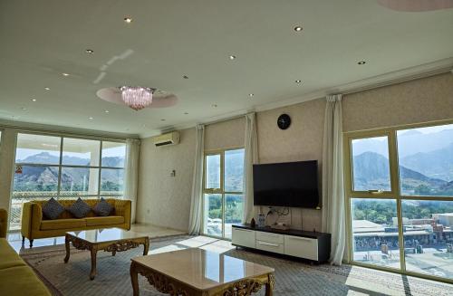 a living room with a couch and a tv at Mountain Majesty 4 Bed Home - BBQ Retreat in Masāfī
