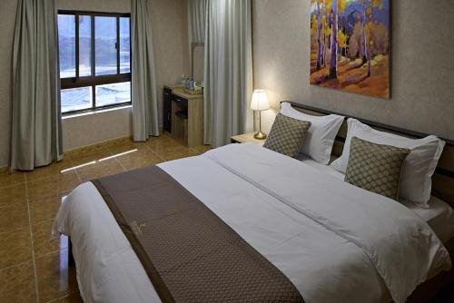 a bedroom with a large white bed with a window at Mountain Majesty 4 Bed Home - BBQ Retreat in Masāfī