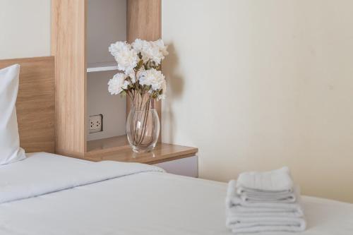 a vase of flowers sitting on a table next to a bed at HN ETH Vinhomes D'capitale Resident - Tran Duy Hung St in Hanoi