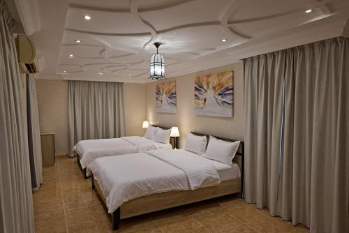 a bedroom with two beds and a chandelier at Mountain Majesty 4 Bed Home - BBQ Retreat in Masāfī