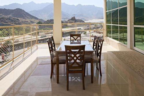 a dining room with a table and chairs on a balcony at Mountain Majesty 4 Bed Home - BBQ Retreat in Masāfī