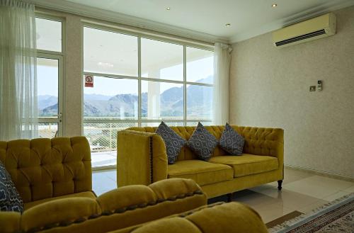 a living room with a couch and a large window at Mountain Majesty 4 Bed Home - BBQ Retreat in Masāfī