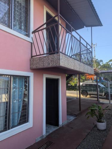 a pink building with a balcony and a door at Departamento Ángeles del Arenal #1 in Fortuna