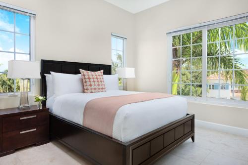 a bedroom with a large bed and two windows at One Grace Bay Townhomes 205 - 2 BR in The Bight Settlements
