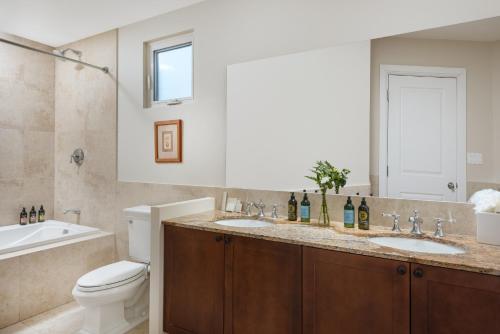 a bathroom with two sinks and a toilet and a tub at One Grace Bay Townhomes 205 - 2 BR in The Bight Settlements