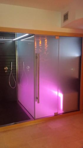 a glass shower door with pink lighting in a room at Albergo Ristorante San Biagio in Montepulciano