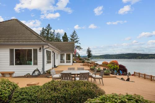 a patio with a table and chairs next to a house at Spacious Beach Front Home on Hood Canal in Belfair