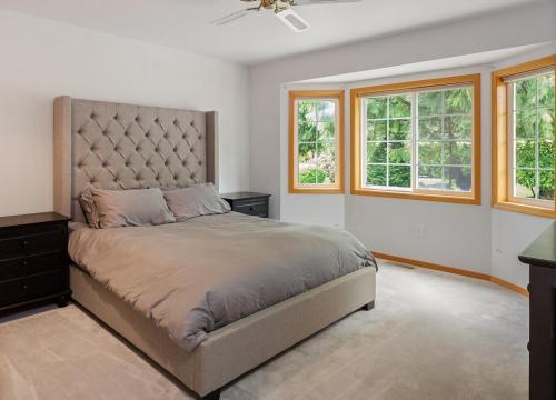 a bedroom with a large bed and two windows at Spacious Beach Front Home on Hood Canal in Belfair