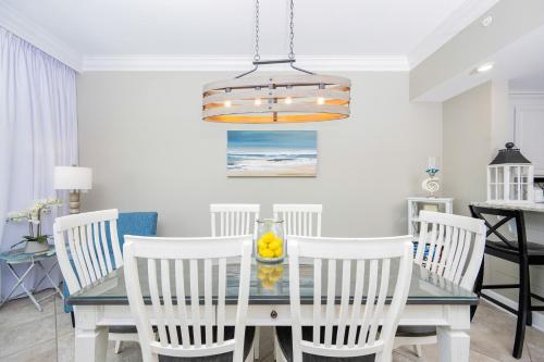 a dining room with a glass table and white chairs at Phoenix Orange Beach II 603 condo in Orange Beach