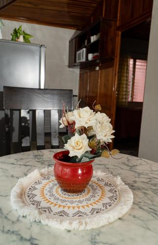 a red vase filled with white flowers on a table at Departamento Ángeles del Arenal #1 in Fortuna