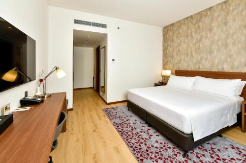 a bedroom with a white bed and a desk and a bed sidx sidx at Comfort Hotel Riyadh Olaya in Riyadh