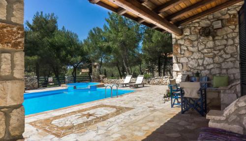 a swimming pool in a yard with a stone building at Villa Nephos in Koiliomenos
