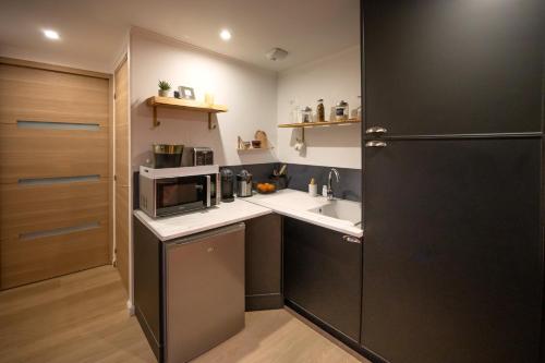 a small kitchen with a sink and a microwave at Au Fil de l'Hôte in Domart-en-Ponthieu