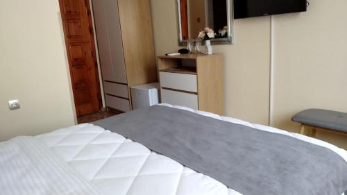 a bedroom with a white bed and a mirror at Victoria Family Hotel in Balchik