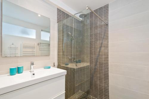 une salle de bain avec une douche, un lavabo et un miroir dans l'établissement Biarritz Surf Appartements 300m de la plage, à Biarritz