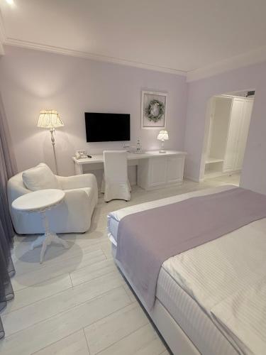 a white bedroom with a bed and a desk and a tv at Krystal Boutique Mansion in Hunedoara