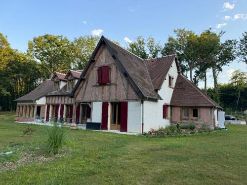 une vieille maison avec des volets rouges sur un champ dans l'établissement Maison pour vacances ou fêtes de famille L'Orée de Clénord, à Mont-près-Chambord