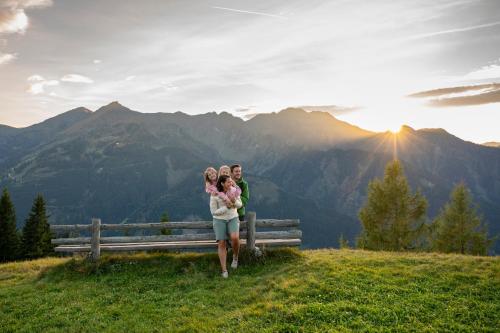 a family standing on a hill with the mountains in the background at Appartements KATHRIN in Grossarl