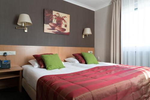 a bedroom with a large bed with red and green pillows at Landhotel Heuvelzicht in Schin op Geul