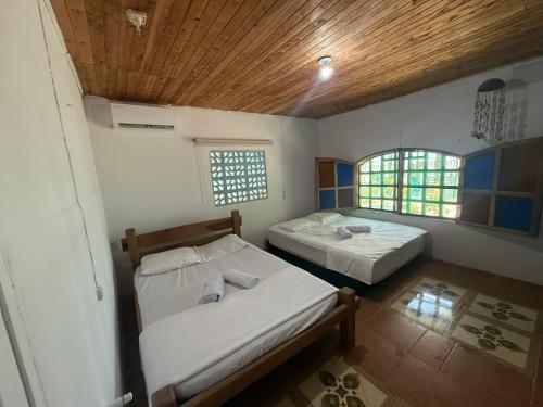 a room with two beds and a wooden ceiling at Espectacular cabaña frente al mar in Paso Nuevo