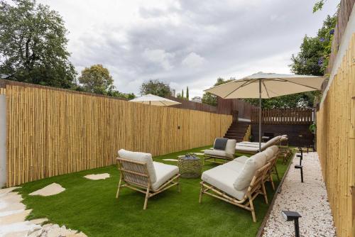 a backyard with chairs and an umbrella and grass at Liiiving in Porto - Pool Paradise Apartments in Porto