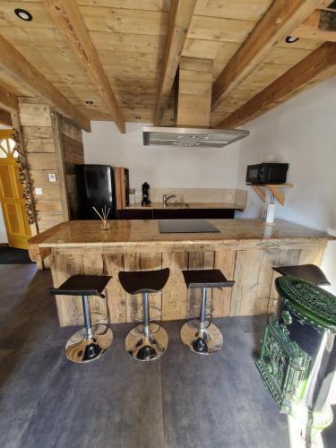 - une cuisine avec un grand comptoir en bois et des tabourets de bar dans l'établissement L'Escouflette, à Rochesson