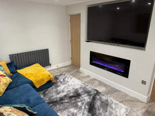 a living room with a blue couch and a flat screen tv at Luxurious Modern House With Garden Close To City Centre in Cardiff