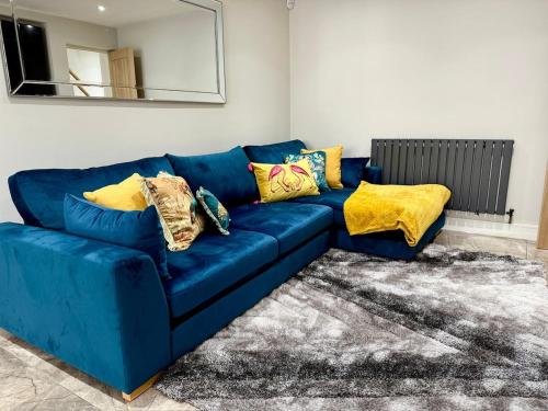 a blue couch in a living room with yellow pillows at Luxurious Modern House With Garden Close To City Centre in Cardiff