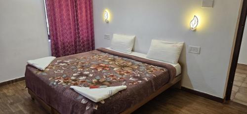 a bedroom with a bed with a flower blanket on it at Fortune Retreats in Ooty