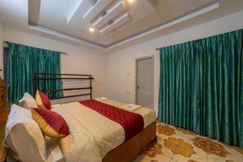 a bedroom with a large bed with green curtains at Fortune Retreats in Ooty