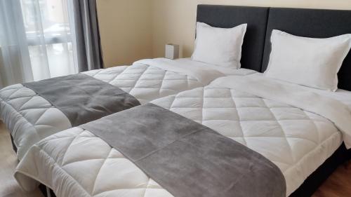 two beds with white blankets and pillows in a bedroom at Victoria Family Hotel in Balchik