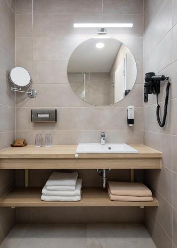 a bathroom with a sink and a mirror at Hunguest Hotel Flóra in Eger
