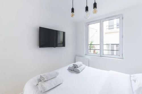 une chambre blanche avec un lit et une télévision dans l'établissement Trail Fishmonger Cosy Apartment 4P, à Paris