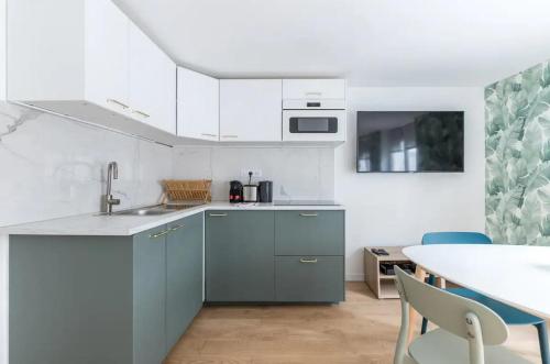 une cuisine avec des armoires blanches et une table avec des chaises dans l'établissement Trail Fishmonger Cosy Apartment 4P, à Paris