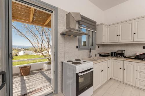 a kitchen with a stove top oven next to a window at Touch Naxos Sunset in Galanado