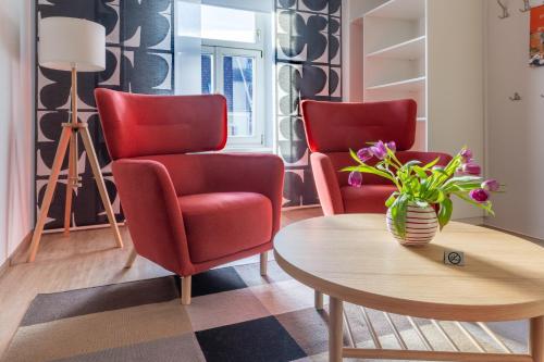 a living room with two red chairs and a table at Platzfaerberhaus in Obdach