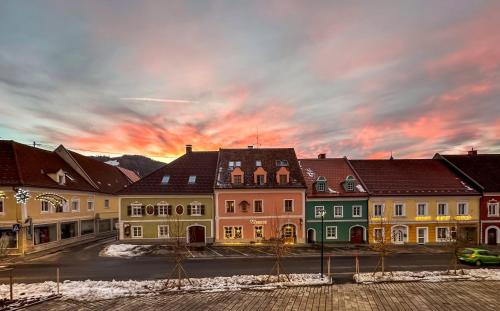 a group of buildings with a sunset in the background at Platzfaerberhaus in Obdach