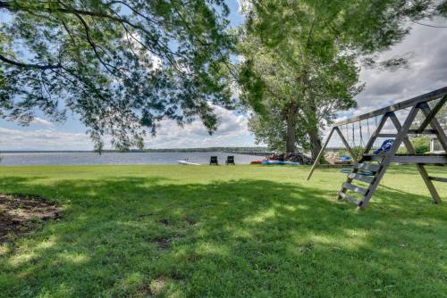 a swing in the grass next to a lake at Lakefront Retreat with Shared Dock and Fire Pit! in Swanton